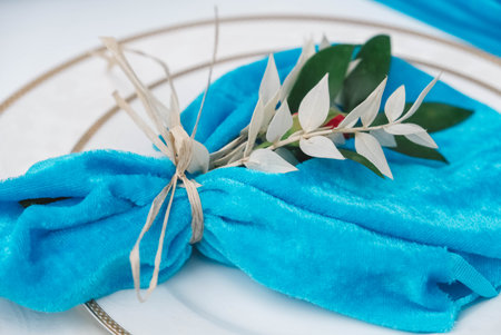 White banquet table covered with blue cloth, served with plates, cutlery, glasses, candles and flower arrangements. Top view. Copy, empty space for text.の写真素材