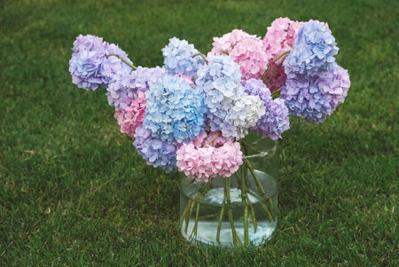 Bouquet of colorful flowers in a glass jar on a background of green grass. Copy, empty space for text.の写真素材