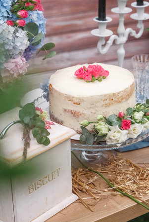 White wedding cake decorated by flowers standing of festive table. Copy, empty space for text.の写真素材