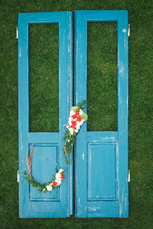 Decorated wreath of flowers, leaves and dry grass on a wooden blue door background. Copy, empty space for text.の写真素材