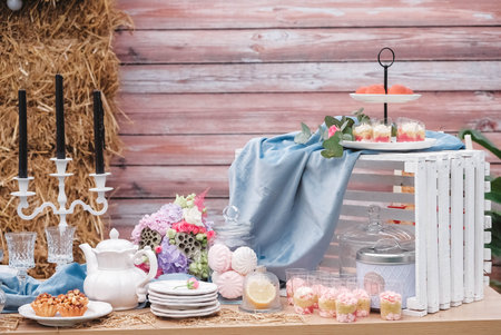 Banquet dessert table decorated in a rustic style decorated with plates, cutlery, glasses, candles and flower arrangements. Copy, empty space for text.の写真素材