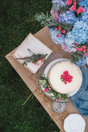 White wedding cake decorated by flowers standing of festive table. Top view. Copy, empty space for text.の写真素材