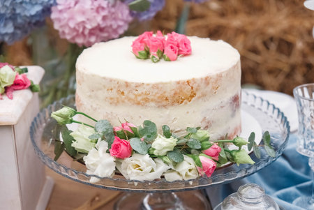 White wedding cake decorated by flowers standing of festive table. Copy, empty space for text.の写真素材