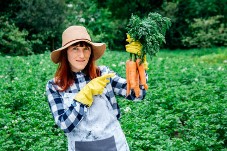 Portrait beautiful female farmer smiling at the camera wearing a straw hat and surrounded by the many plants in her vegetable garden.の写真素材