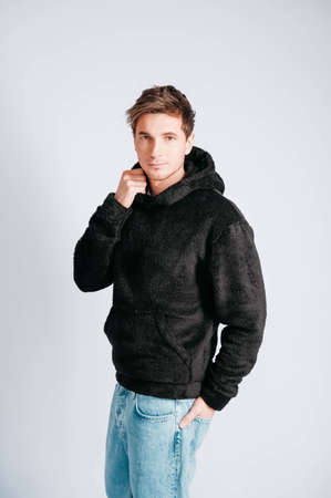 Man in black sweatshirt with hood on a white background. Copy, empty space for textの写真素材