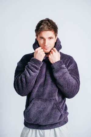 Portrait of a young man in purple sweatshirt with hood on a white background. Copy, empty space for textの写真素材