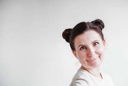 Woman with pigtails and a funny face wearing a T-shirt on a white background. Copy, empty spaceの写真素材
