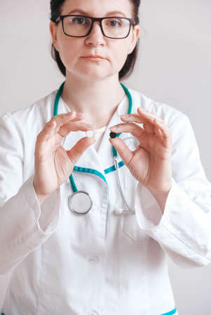 Woman doctor with pills in her hands on a white background. Taking vitamins or medications. Copy, empty space for text.の写真素材