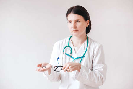 Woman doctor with pills in her hands on a white background. Taking vitamins or medications. Copy, empty space for text.の写真素材
