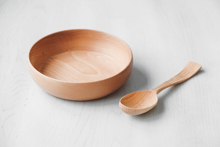 Empty wooden bowl and wooden spoon on a white table background. top view. Copy, empty space for textの写真素材