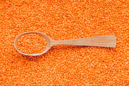 Raw red lentils in a wooden spoon as background texture.の写真素材