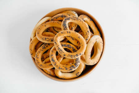 Dried bagels with poppy seeds in a wooden bowl on a white background.の写真素材