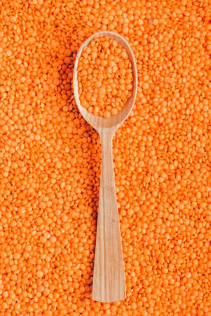 Raw red lentils in a wooden spoon as background texture.の写真素材