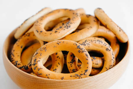 Dried bagels with poppy seeds in a wooden bowl on a white background.の写真素材