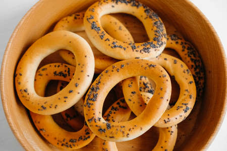 Dried bagels with poppy seeds in a wooden bowl on a white background.の写真素材
