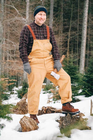 Portrait of a man lumberjack with an ax in his hands on a background of forest and trees
