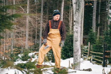 Portrait of a man lumberjack with an ax in his hands on a background of forest and treesの写真素材