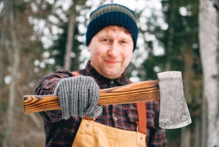 Portrait of a man lumberjack with an ax in his hands on a background of forest and treesの写真素材