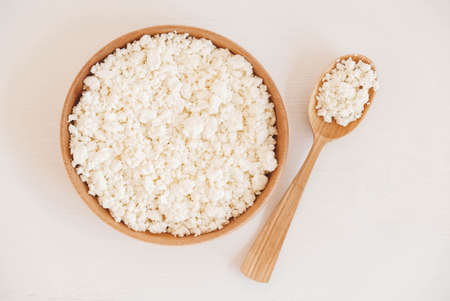 Cottage cheese in a wooden plate with a spoon on a white background.の写真素材