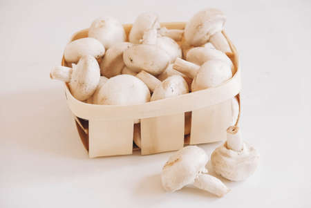 Champignon mushrooms in a wicker basket on a white background.の写真素材