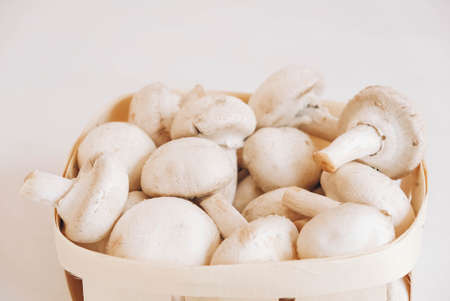 Champignon mushrooms in a wicker basket on a white background.の写真素材