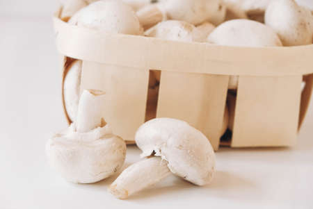 Champignon mushrooms in a wicker basket on a white backgroundの写真素材