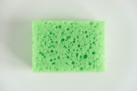 Green sponge for cleaning on a white background.