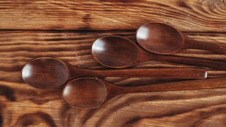 Wooden spoons from dark wood on a wooden table background.の写真素材