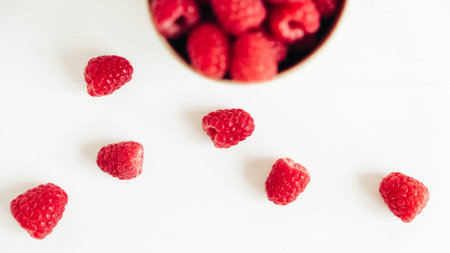 Fresh red raspberries in a paper cup on a white table background.の写真素材