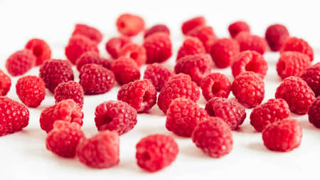 Fresh red raspberries in a paper cup on a white table background.の写真素材