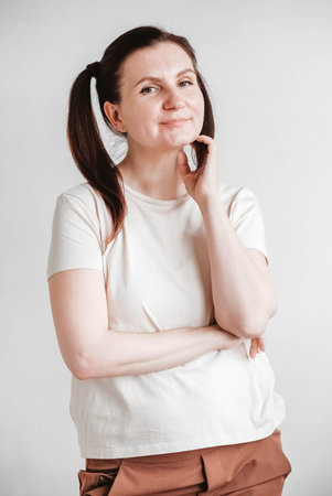 Beautiful woman with pigtails and a funny face wearing a T-shirt on a white background. Copy, empty...