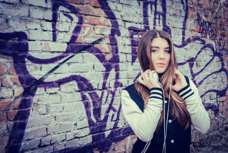 Teenage girl  with headphones posing near graffiti wallの写真素材