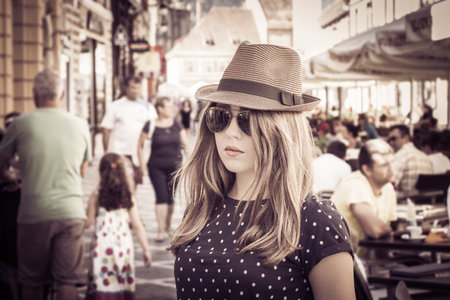 Portrait of a tourist girl in a hat on a crowded streetin Brasov. Romania. Retro style effect