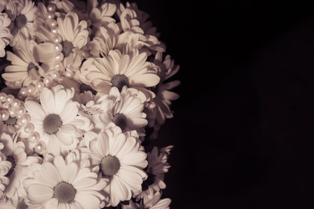 Bouquet of white and yellow chrysanthemum and white pearls necklace on a black bachground. Vintage...