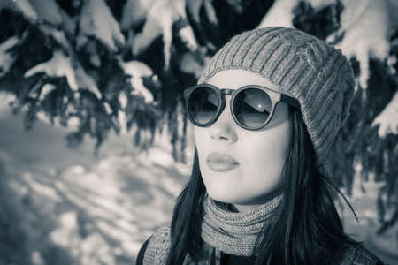 Portrait close up of a pretty young woman in sunglasses and winter outfit outdoor. Black and whiteの写真素材