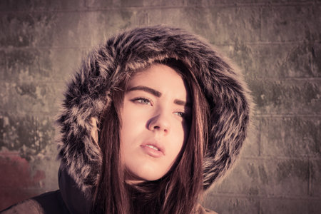 Portrait close up of a teenage girl outdoor wearing winter coat with the faux - fur hood on. Toned...