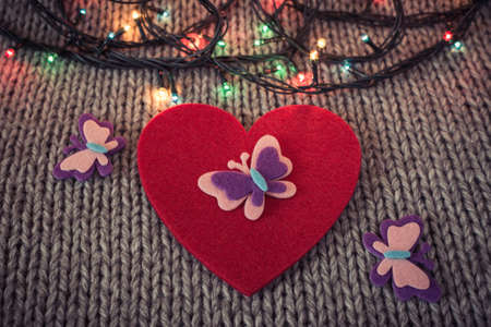 Red felt heart with colorful butterflies, colorful garland with woollen texture in the background. Valentine's  themeの写真素材