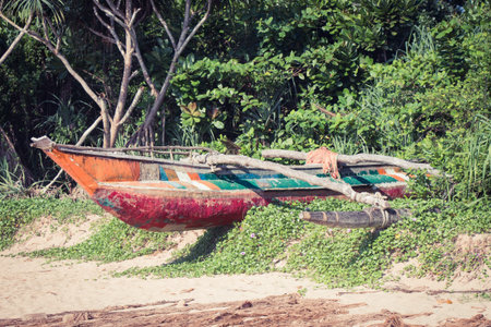 Fishing boat and a fragment of a fishing net on a tropical beach with mangrove in the backgroundの写真素材