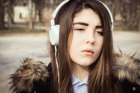 Outdoor close up portrait of a pretty teenage girl with headphones. Toned effectの写真素材