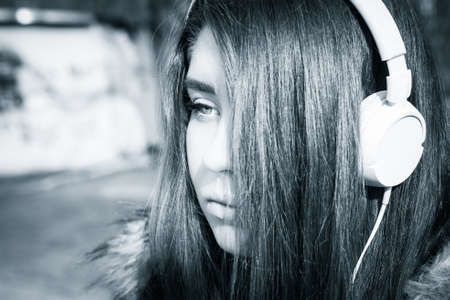 Outdoor close up portrait of a pretty teenage girl with headphones. Black and whiteの写真素材