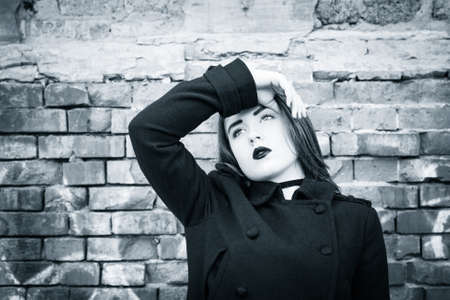 Portrait of a teenage girl with black lipstick posing next to an old brick wall. Black and whiteの写真素材