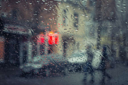 Rainy city street seen through the car windshield with focus on some water drops. Toned effectの写真素材