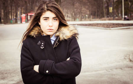 Outdoor portrait of a thoughtful teenage girl wearing a black coat.の写真素材