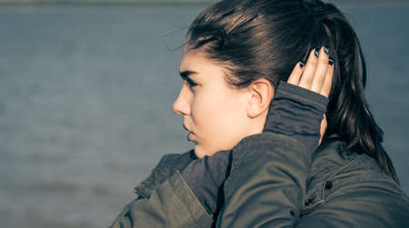 Outdoor portrait in profile of a thoughtful teenage girl. Toned effectの写真素材