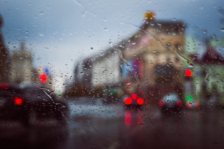 City road seen through rain drops on the car windshield. Focus is on some water drops