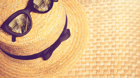 Straw hat with black trendy sunglasses with reflection of palms in them on a straw bag. Beach summer vacation theme concept.の写真素材