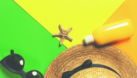 Beach accessories on a bright colorful background. A fragment of a straw hat, dried starfish, a...