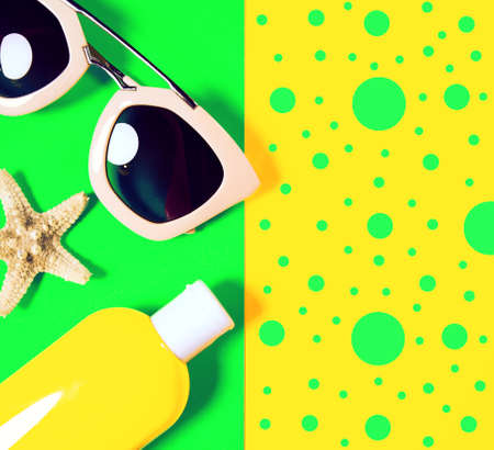 Beach accessories on a bright colorful background. Dried starfish, trendy pink sunglasses and a bottle of sunscreen lotion. Summer vacation background.Top view Image with copy spaceの写真素材