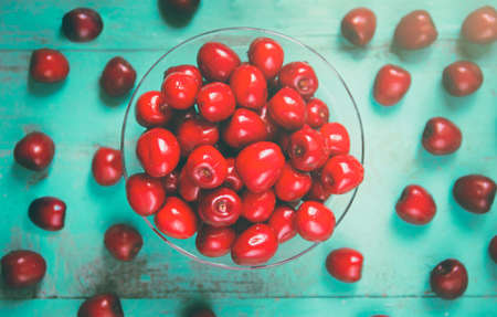 Fresh red cherry in a bowl on an old painted wooden table as a bright colorful summer background for seasonal cards, posters, blogs, web designの写真素材