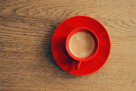 Red cup of coffee on a wooden table. Top viewの写真素材